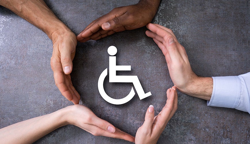 A group of hands, all with different coloured skin tones, create a circle around a sign for disability.