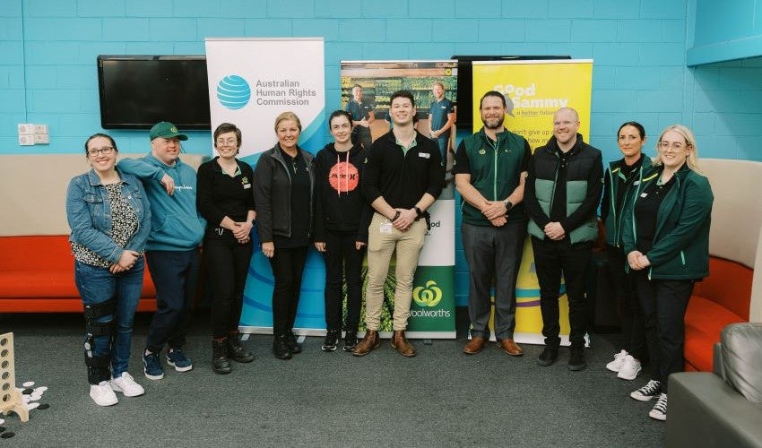 Image of a group of people standing in front of banners from the Australian Human Rights Commission, Good Sammy and Woolworths. 