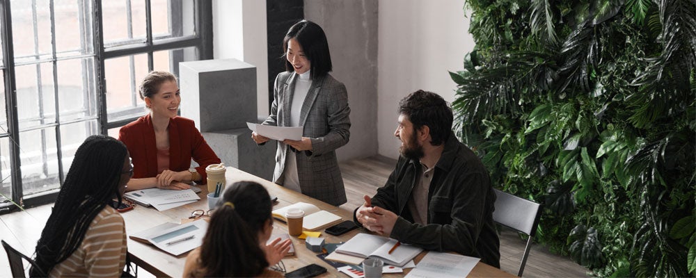 High angle portrait of diverse group of business people meeting at table in modern office interior decorated by plants.