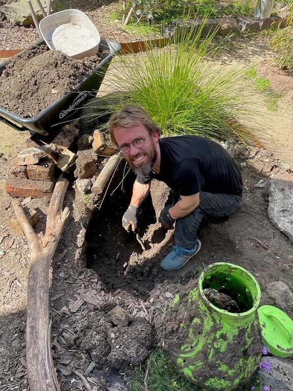 Sam Drummond smiles to camera while gardening