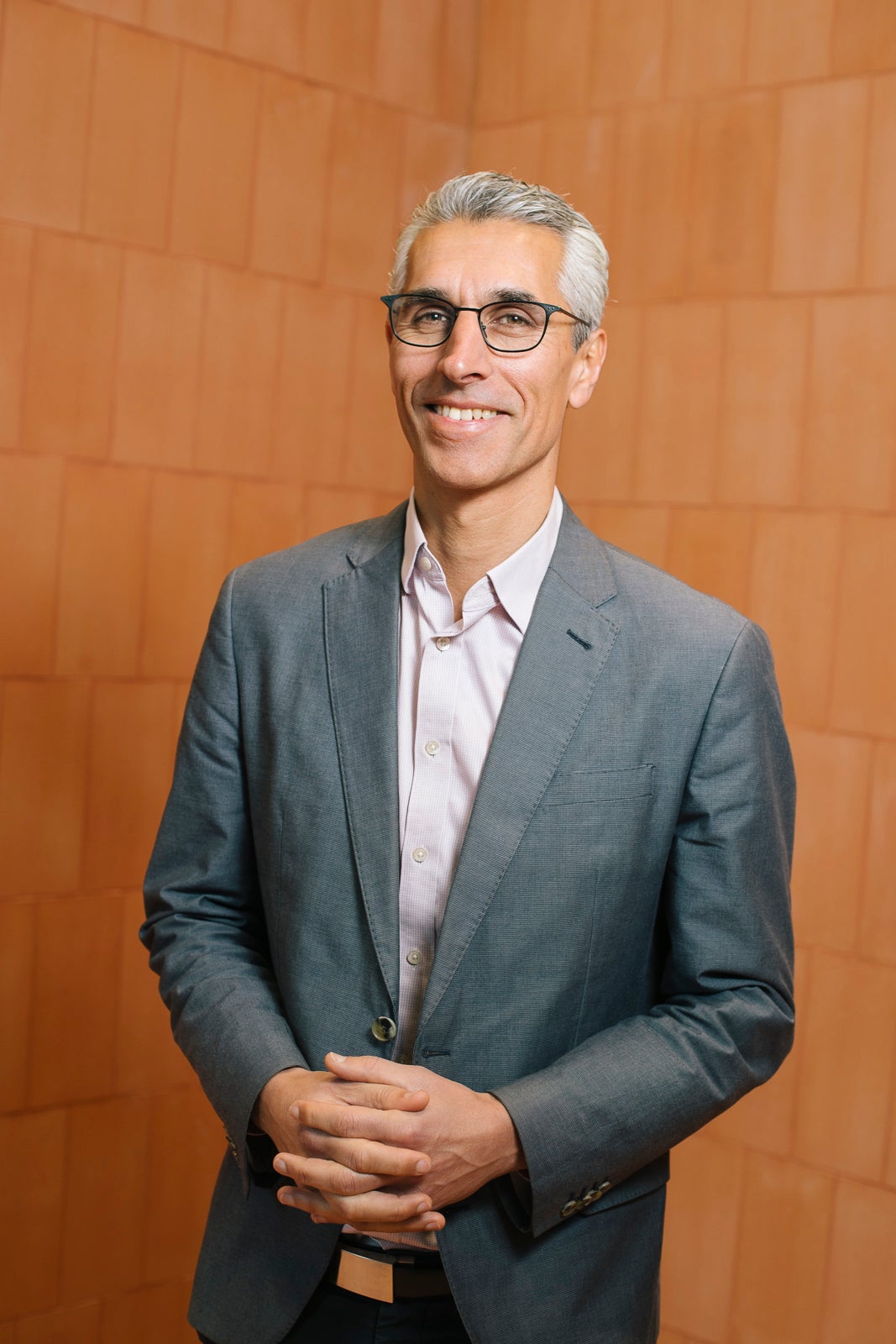 Human Rights Commission President, Hugh de Kretser. Smiling, middle aged man in grey suit with white hair and glasses