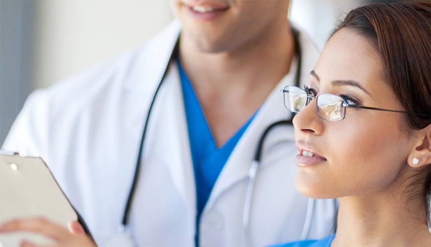 Female nurse reading chart with male colleague