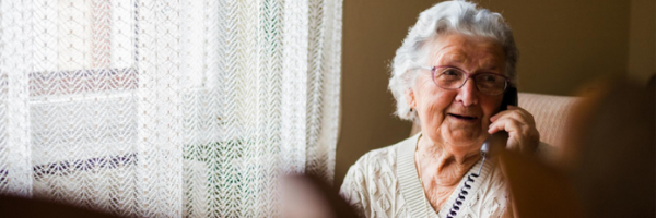 Older woman seated in living room talking on phone