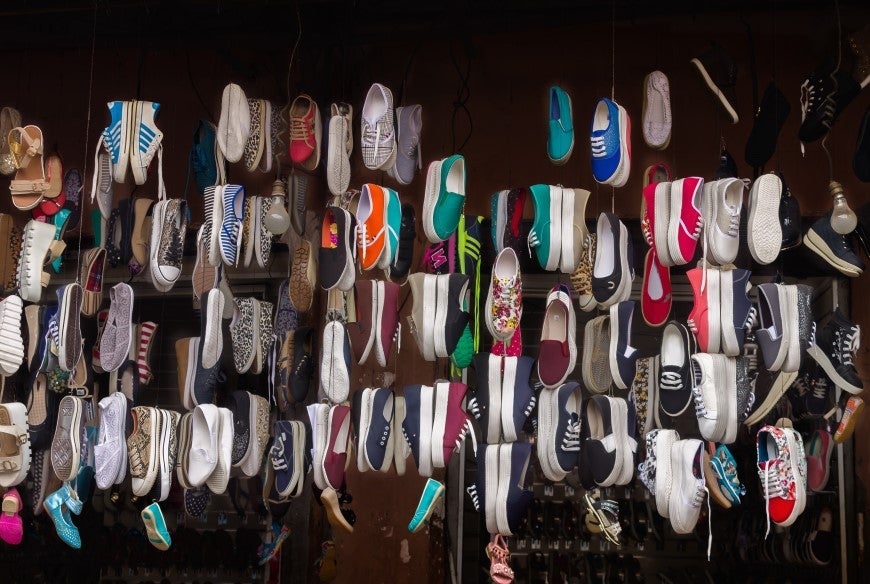 Image of a range of different colours and styles of sneakers hanging in a store front 