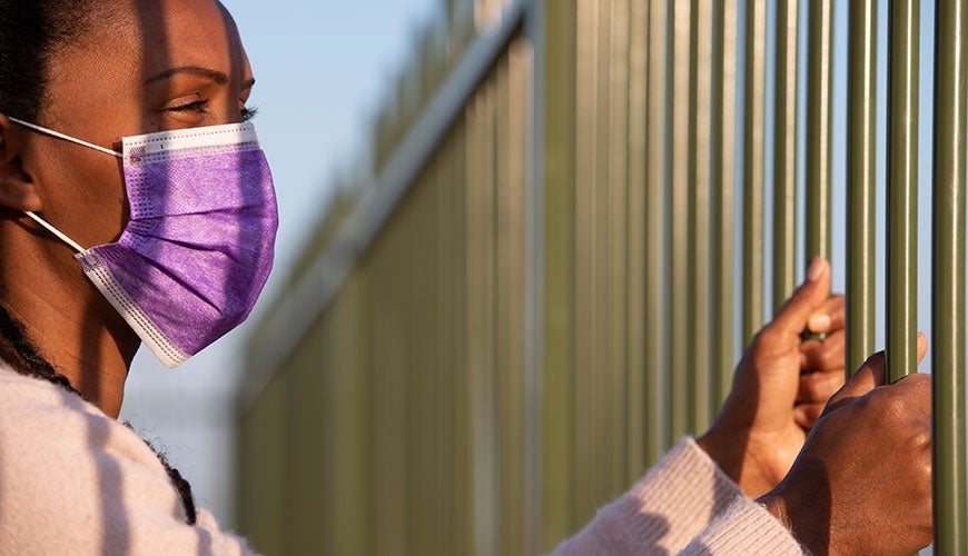 woman in facemask in detention fence