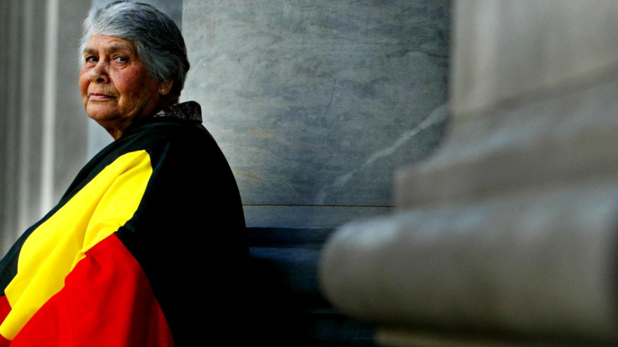 Side profile image of Dr Lowitja O'Dongohue wrapped in the Aboriginal Flag