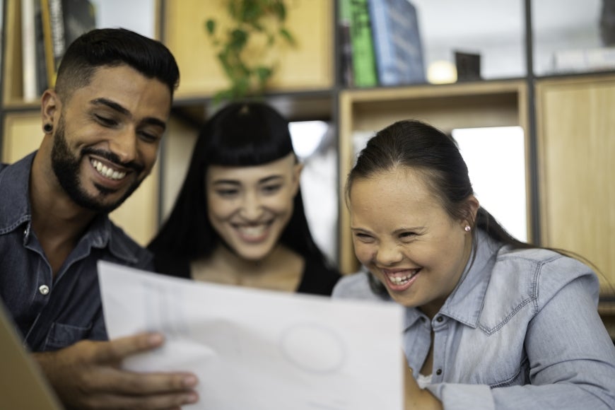 Group of business people (including Special Needs Woman) discussing new project at modern startup office stock photo.