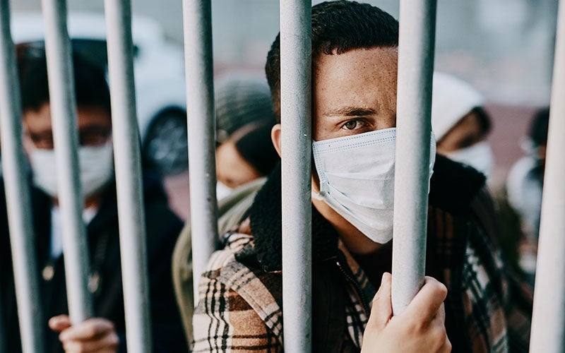 Detainees look from behind steel fence