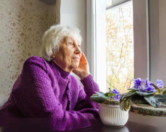 An older person looking out a window