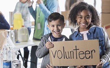 students holding a volunteer sign