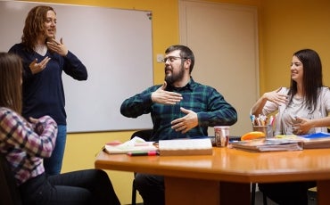 People in a staff meeting, communicating with sign-language