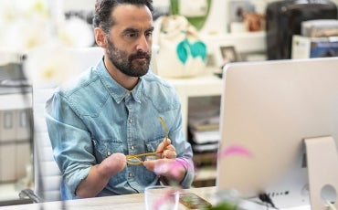 A person with a disability sits working at a laptop