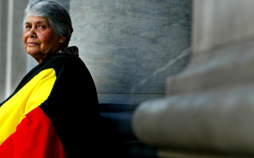 Side profile image of Dr Lowitja O'Dongohue wrapped in the Aboriginal Flag