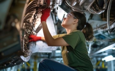 A proud and confident female aerospace engineer works on an aircraft, displaying expertise in technology and electronics.