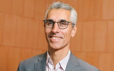 Human Rights Commission President, Hugh de Kretser. Smiling, middle aged man in grey suit with white hair and glasses