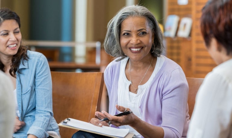 A senior lady at work in a meeting with 2 other females.