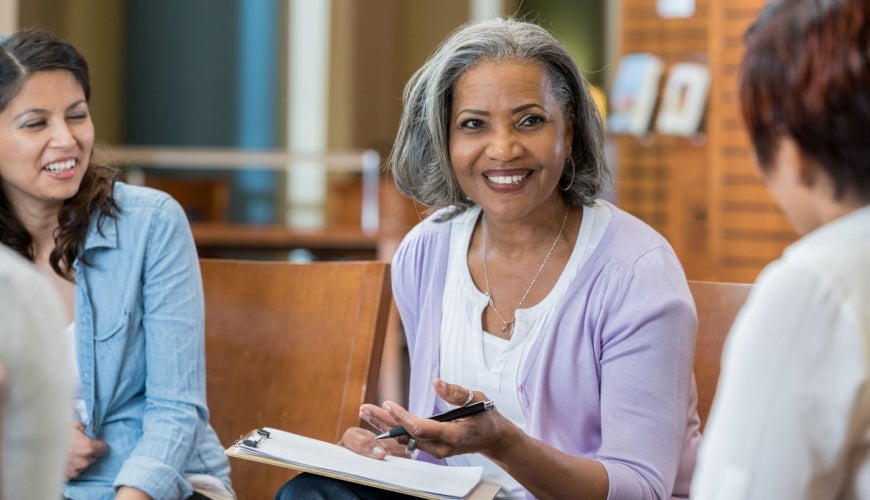 A senior lady at work in a meeting with 2 other females.