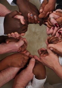 Many black and while hands linked together