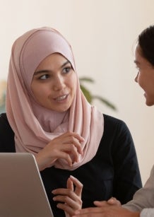 Multicultural businesswomen brainstorm cooperating at office meeting.