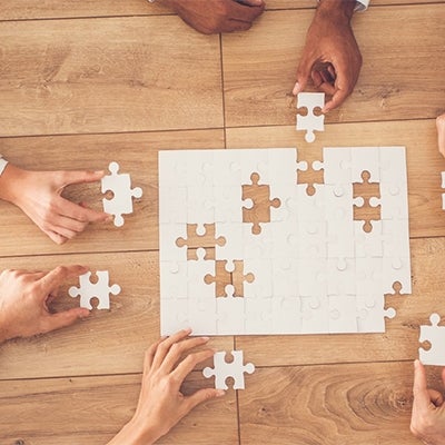 workers' hands assembling a jigsaw