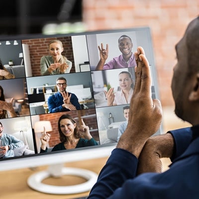 A man of colour participating in a zoom meeting. He is signing to the other 9 participants.