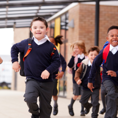 A group of children running at a school, wearing school uniforms