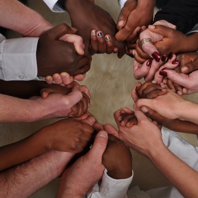 Many black and while hands linked together