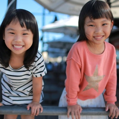 Two Asian girls smiling happily playing outdoors.